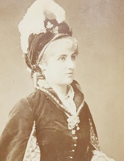 Half length, sepia-toned portrait of an elegantly dressed woman wearing a plumed hat. She is slightly turned to the photographer's right and gazing off camera in that direction. 