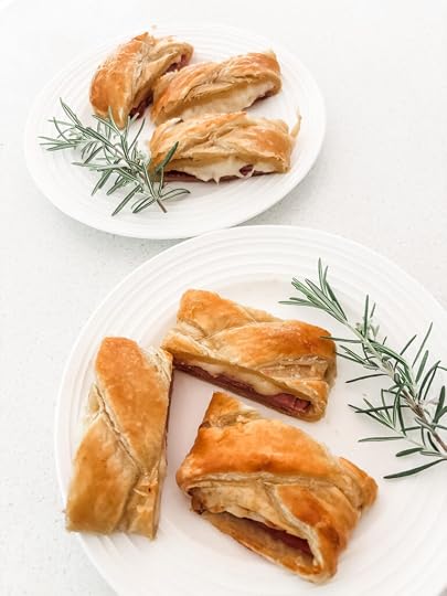 Sliced ham and cheese strudel on a white serving board showing flaky golden pastry and melted Swiss cheese filling