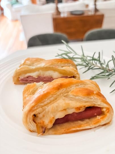 Sliced ham and cheese strudel on a white serving board showing flaky golden pastry and melted Swiss cheese filling