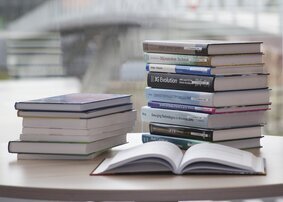 Two stacks of books with an open book in front