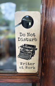 Card hanging on doorknob with image of vintage typewriter saying Do Not Disturb