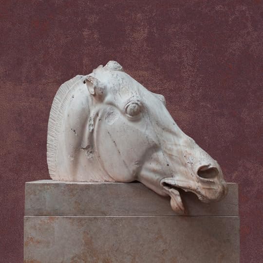 A statue of a horse head sits atop a stone pedestal in front of a pinkish purple concrete wall. The horse is exhausted, mouth ajar, nostrils flared.
