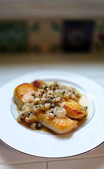 A plate of walleye with white currant sauce on a white tile counter.