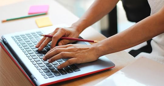 Persona usando una laptop mientras sostiene un lápiz entre los dedos