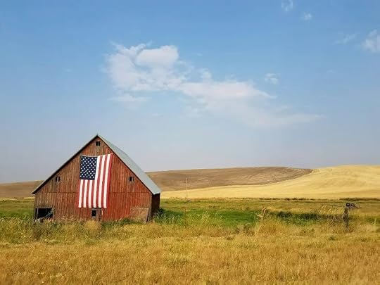 A barn in a field with an American flag