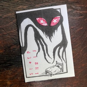 Sleep fight zine shows a silhouetted demon with long creepy arms and printed red eyes looming over a tiny bed
