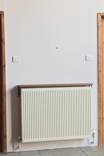 A magnolia style colour radiator is on a wall that is another version of magnolia, just with a little bit of grey stone in it.