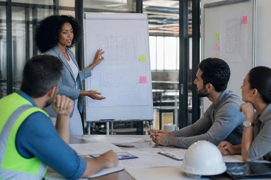 A diverse group of engineers and project managers engaged in discussion during a workshop, with flip charts and notes on the wall, natural lighting, collaborative atmosphere