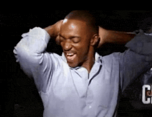 a man with his hands behind his head is wearing a blue shirt with the letter g on it
