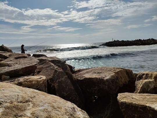 Silhouettes of people fishing at the Muthalapozhi rock breakwaters.