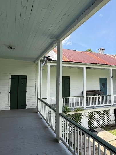 Gallery porch at Woodland Plantation, with green shutters and a rusted tin roof