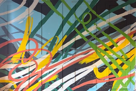 Photo of a wall with two rows of four evenly spaced rectangluar frames. Large, bright, colorful paint strokes overlap everything at freeform angles.