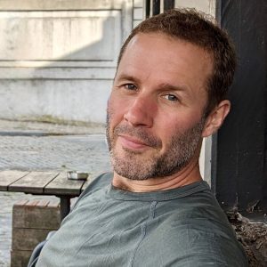 Dave Haines, a handsome man in his 40s with short brown hair and a light beard smiling at the camera.