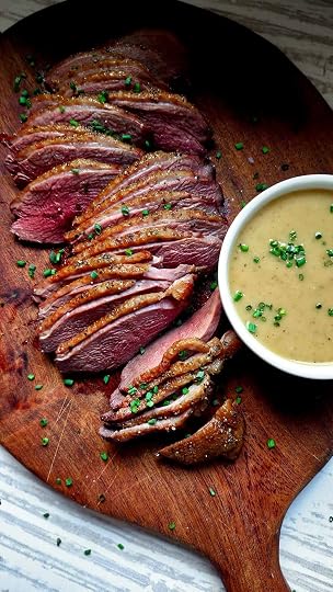 Sliced goose breast on a platter with a ramekin of sauce Robert.