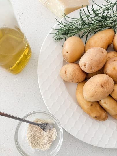 Ingredients for crispy smashed potatoes laid out on a counter, including baby Yukon Gold potatoes, olive oil, kosher salt, and fresh ground pepper