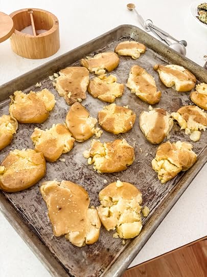 A tray of smashed potatoes brushed with olive oil and sprinkled with salt and pepper, ready for the oven