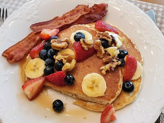 Pancakes covered in syrup, berries, and walnuts