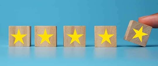 four gold stars on wooden blocks against a light blue background. a fifth gold star is being placed next to them