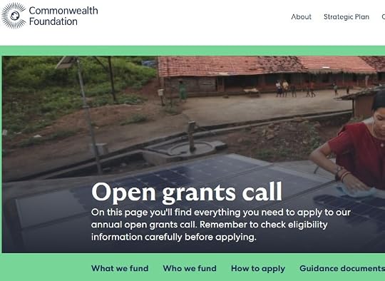 A woman working on a solar panel installation in a rural setting, with traditional houses in the background, promoting the Commonwealth Foundation's open grants call.