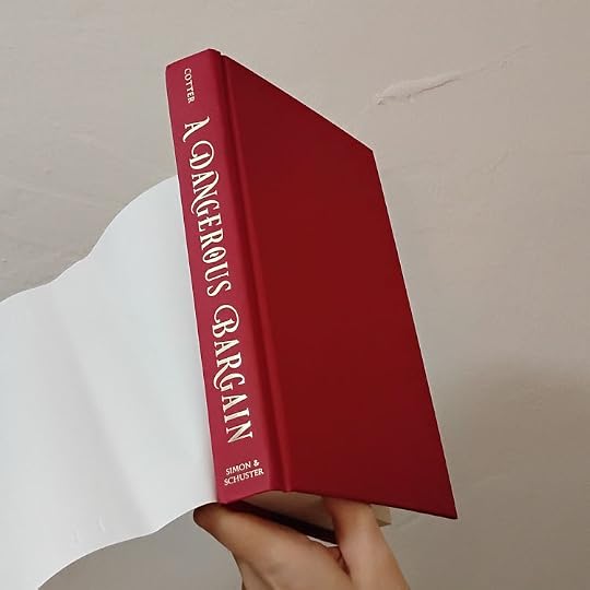 Photo of A Dangerous Bargain by Erin Cotter hardcover with the dust jacket flipped back to show the vibrant red book with slightly gold-ish lettering on the spine.
