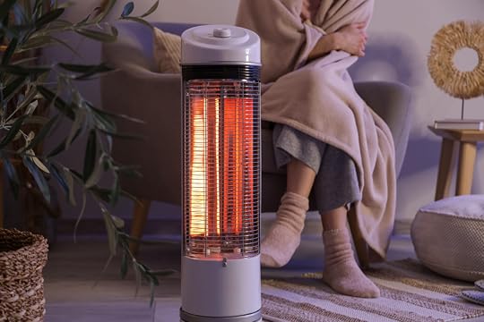Young,Woman,With,Electric,Heater,And,Blanket,Sitting,On,Armchair