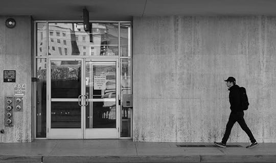 Person walking past a concrete building in black and white