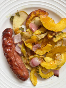 Delicata squash and chicken sausage sheet pan dinner with roasted squash half-moons, red onion, apple, sage, and browned sausages