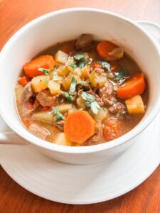 A bowl of healthy beef and beer stew with lean beef, potatoes, carrots, and celery in a rich savory broth