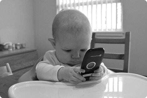 A very smol child plays with a mobile phone
