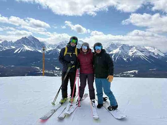 three people in ski gear on top of a ski hill