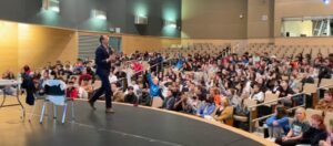 Students raising their hands during an interactive middle and high school respect assembly in a school auditorium.