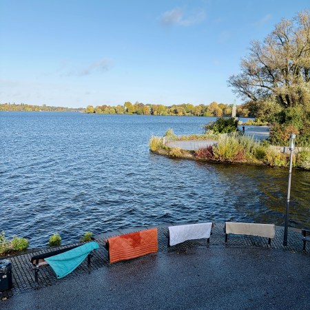 Blick über die Außenalster, im Vordergrund nasse Schlafsäcke und Decken, zum Trocknen über Bänke gelegt.